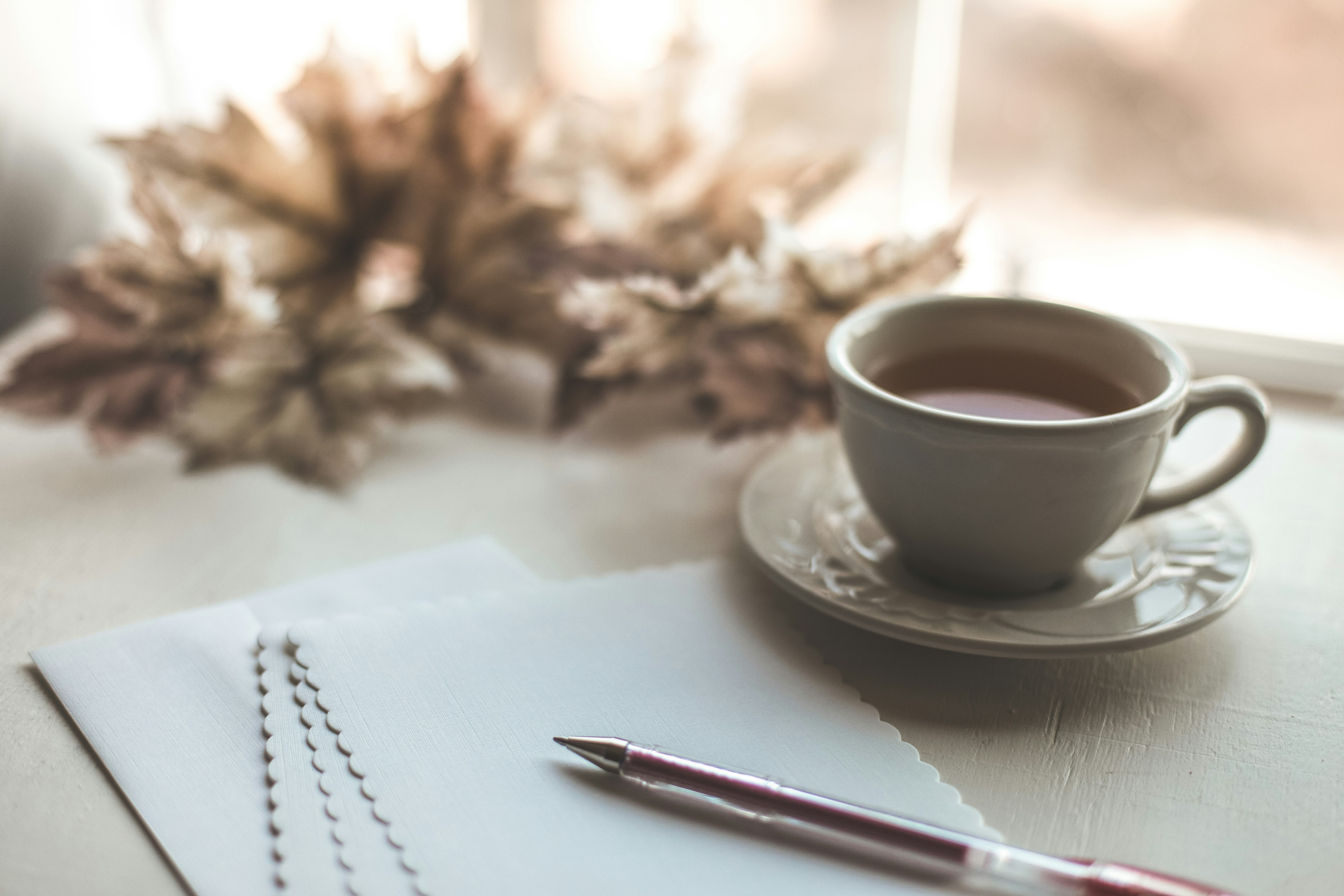 white ceramic cup on white ceramic saucer beside red click pen